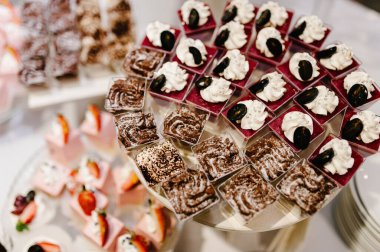 Güzel masa. Böğürtlenli kremalı kek ve kek. Şekerli masa, şeker, açık büfe. Parti şekerlemeleri için tatlı masası. Kapatın. Restoranda dekore edilmiş parti resepsiyonu. Çikolata