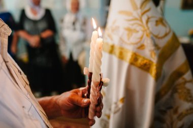 İnsanlar el ele tutuşup düğün mumlarını yakıyor. Mumu yak. Hristiyan kilisesinde düğün töreninde ellerinde mum tutan ruhani bir çift. Kapat..
