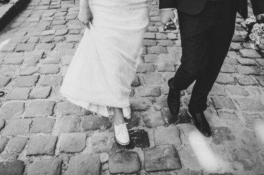 Gelin ve damat kaldırımda yürür ve yürür, şehrin caddesi boyunca bir yürüyüş sırasında el ele tutuşurlar. Alt manzara. Açık havada yeni evliler..