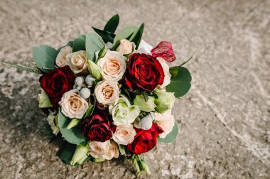 Gri arka planda çiçeklerden yapılmış renkli bir düğün buketi yatıyor. Gelinin caddedeki buketi. Hiç kimse. Üst görünüm.