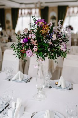 Büyük bir buket taze pembe, mavi, beyaz çiçekler ve vazoda yeşillik. Düğün çiçekleri, gelin buketi yakın plan. Masada dekorasyon, klasik tarzda. Dekorasyon nesneleri.