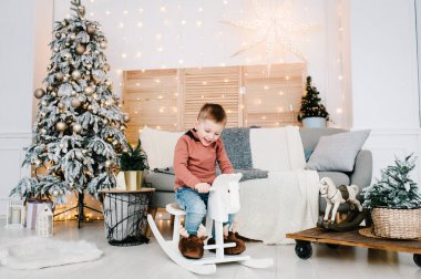 Çocuk Noel ağacının yanında oynuyor. Mutlu yıllar ve mutlu Noeller. Noel dekore edilmiş iç mekan. Aile tatili kavramı.