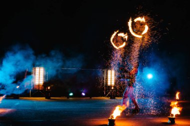 Ateş gösterisi, ateşle dans etmek, havai fişeklerle hokkabazlık yapan erkek üstat, açık havada gösteri, karanlıkta ateşli bir figür çizer, gece parlak kıvılcımlar. Takım elbiseli bir adam Ateşle dans ediyor.