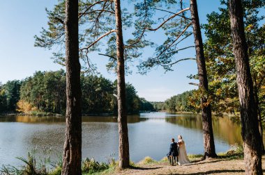Düğün anı, göle bakan bir çift yeni evli, parkta doğaya bakan. Göl kenarında düğün töreni..
