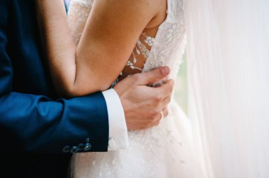 Gelin ve damat doğanın önünde birbirlerine sarılıyorlar. Yan görünüm.