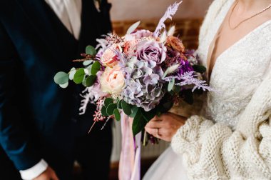 Damat ve gelin ellerinde bir buketle düğün töreninde duruyorlar..