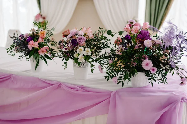 Big bouquet of fresh pink, blue, white flowers and greenery in vase. Wedding flowers, bridal bouquet closeup. Decor on table, vintage style. Decoration objects.