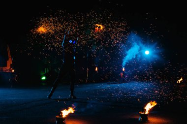 Ateş gösterisi, ateşle dans etmek, havai fişeklerle hokkabazlık yapan erkek üstat, açık havada gösteri, karanlıkta ateşli bir figür çizer, gece parlak kıvılcımlar. Takım elbiseli bir adam Ateşle dans ediyor.