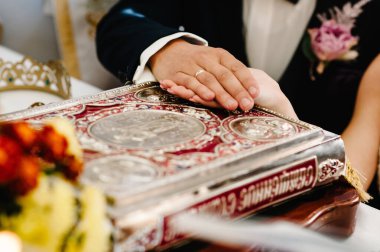 Yeni evliler, kilisedeki düğün töreninde mutlu bir çift. Rahip, kutsal İncil 'i gelin ve damada uzun ömürler versin diye kutsar..