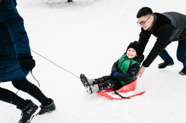 Ebeveynlik, moda, mevsim ve insanların konsepti. Parkta kışın giydiği kıyafetlerle gezen mutlu aile. Mutlu bir yeni yılı ve mutlu noelleri kutlama konsepti.