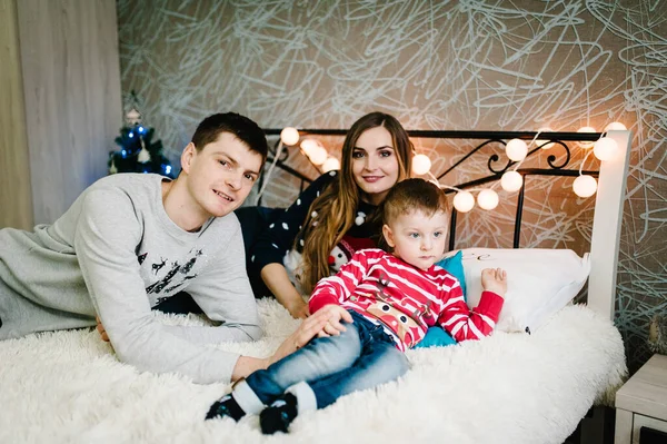 크리스마스 침대에 누워서 클로스 스웨터를 아들에게 사랑의 포옹을 즐기고 휴일을 — 스톡 사진