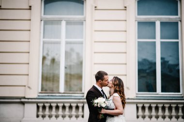 Gelin ve damadın portresi ayakta ve sarılıyor, dışarıda eski binanın yanında öpüşüyorlar, klasik saray havası. Romantik. Sokakta aşk.