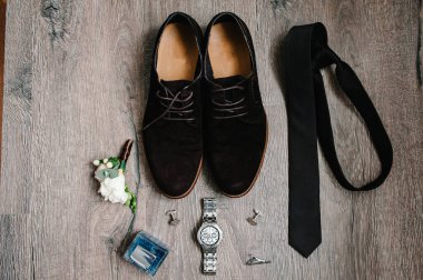 Süet erkek ayakkabıları, saat, parfüm, kravat, kol düğmeleri, damat için çiçek yaka çiçeği. Kırsal kahverengi ahşap arka planda düğün aksesuarları. Fikir kompozisyonu. tatil konsepti. Düz yat. en üstteki görünüm.
