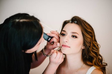 Makyaj sanatçısı modelin yüzüne ve cildine mükemmel makyaj yapar. Kuaför rujla fırça dudakları çizer. Güzel esmer kadın. Yakın plan..