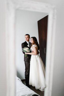 Sanat eserleri, gürültü, tahıl. Sevgili çift, gelin ve damadın kucaklaşması, aynanın karşısında durun. Odadaki aynada yansıyan vücut. Yeni evlilerin düğün portresi..