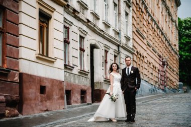 Damat ve gelin portresi eski binanın yanında duruyor, dışarıdaki eski evde, dışarıda. Lviv şehrinin sokaklarında yeni evliler..