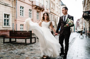 Damat gelinlik içinde, gelin ise buketli eski binanın yanında, eski evin dışında, açık havada yürüyor. Yeni evliler Lviv şehrinin sokaklarında yürüyor..