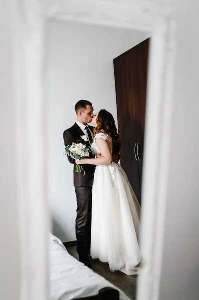 Artwork, noise, grain. Loving couple, bride and groom hugging and kissing indoors, stand in the mirror. Reflection body in the mirror on room. Wedding portrait of newlyweds.