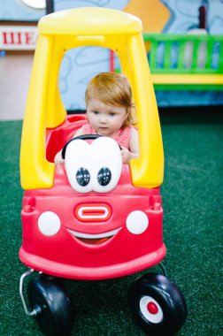 Mutlu çocuklar, küçük kız çocuğu yolda büyük kırmızı bir arabaya biniyor. Kapatın. Bebek arabayı sürüyor ve bir doğum günü partisinde bir çocuk oyun odasında oynuyor. Eğlence merkezinde vakit geçiriyoruz..