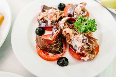 Beyaz tabakta gurme salatası. Peynir, domates, marul dilimleri. Masada beyaz tabak var. Yiyecekler. Tatil.