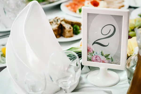Serving, setting table. Plate with silverware cutlery, linen napkin. Wedding table decoration. Stands, sign number 2. Close up.