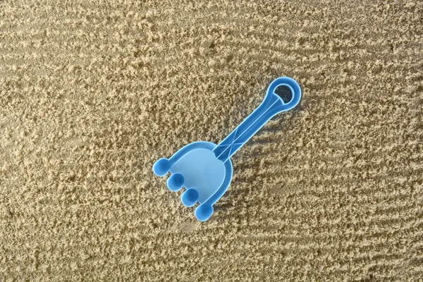 Blue toy rake in the sand — Stock Photo, Image