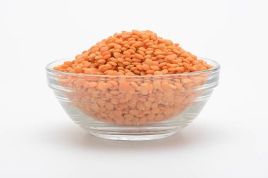 Beyaz arka planda cam bir kasede çiğ turuncu mercimek