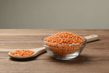 Tabakta çiğ turuncu mercimek ve tahta masada kaşık.