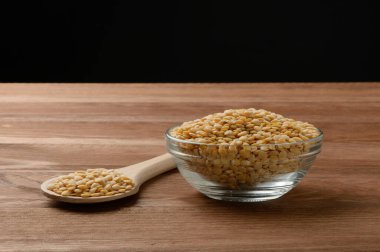 Tabakta çiğ sarı mercimek ve masada tahta kaşık.