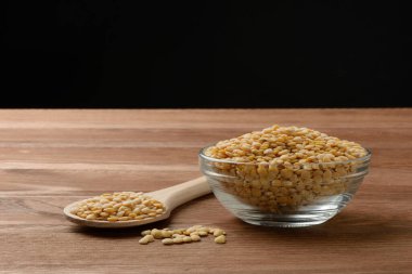 Tabakta çiğ sarı mercimek ve masada tahta kaşık.