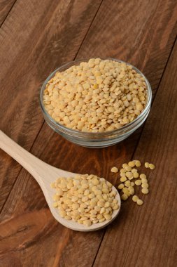 Tabakta çiğ sarı mercimek ve masada tahta kaşık.