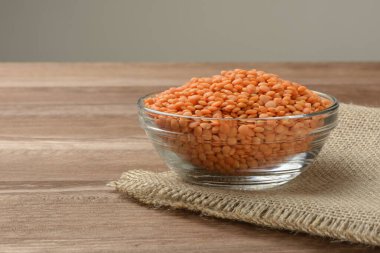 Tahta masadaki bir kasede çiğ turuncu mercimek., 