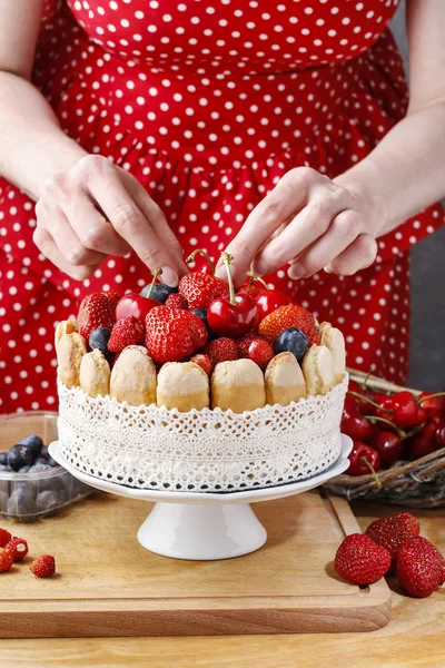 Vrouw met zomer spons cake met vruchten op keramische taart sta — Stockfoto