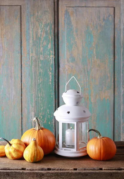 White lantern and colorful pumpkins on wooden table — Stock Photo, Image