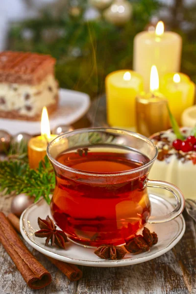 Glass of hot steaming tea among christmas decorations — Stock Photo, Image