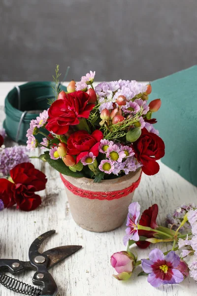 Floristería lugar de trabajo: arreglo floral con claveles rojos y hy —  Fotos de Stock