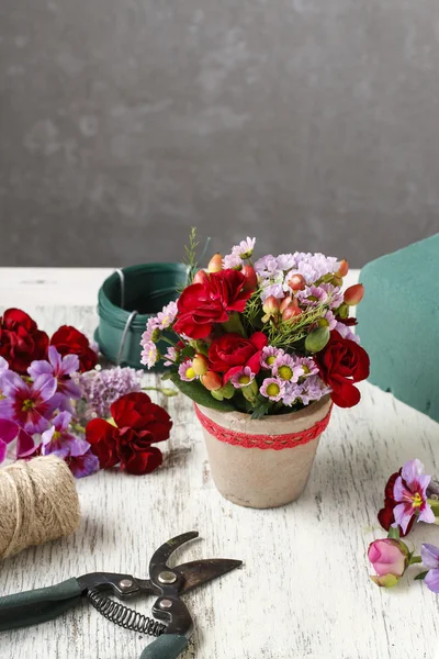 Floristería lugar de trabajo: arreglo floral con claveles rojos y hy — Foto de Stock