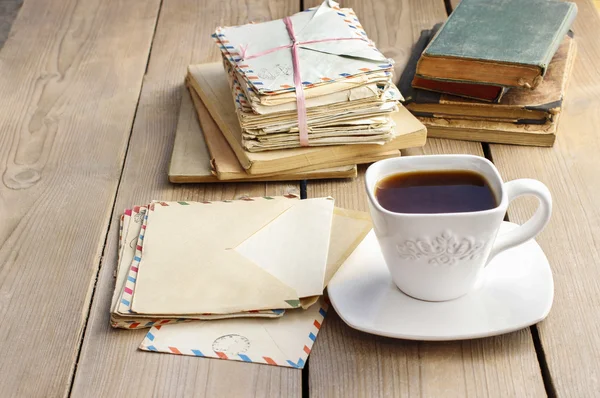 Filiżankę kawy na drewnianym stole. Sztuka książki i stos listów — Zdjęcie stockowe