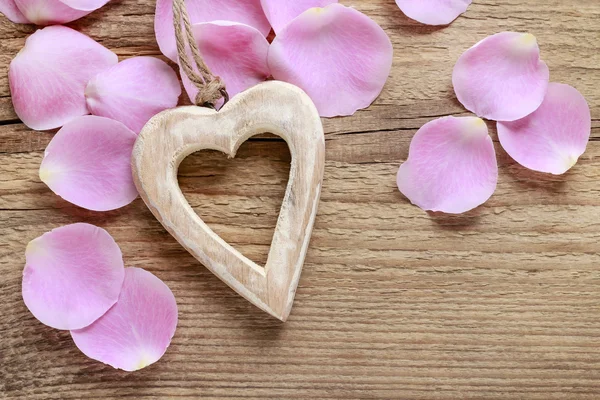 Wooden heart and pink rose petals — Stock Photo, Image