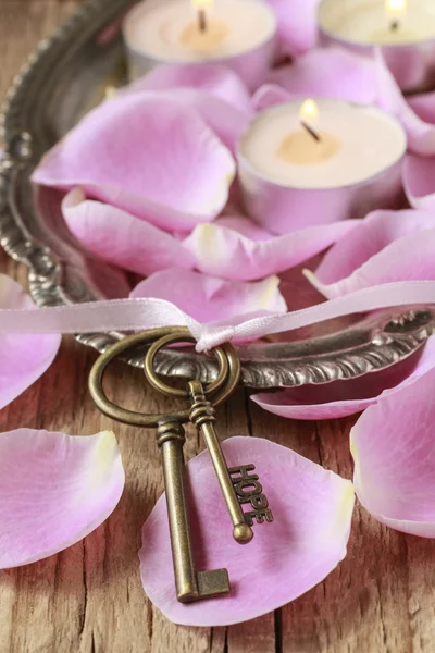 Romantisk vintage nycklar och doftljus bland rosa rosenblad — Stockfoto