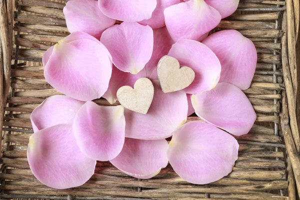 Roze roze bloemblaadjes in een rieten mand — Stockfoto