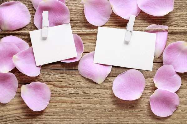 Blank paper card and pink rose petals on wooden background — Stock Photo, Image