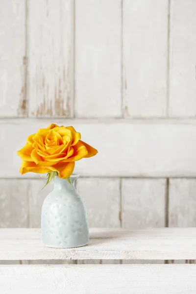 Однократная роза в керамической вазе на деревянном фоне — стоковое фото