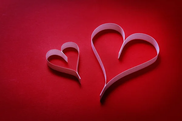 Corazones de papel sobre un fondo rojo —  Fotos de Stock