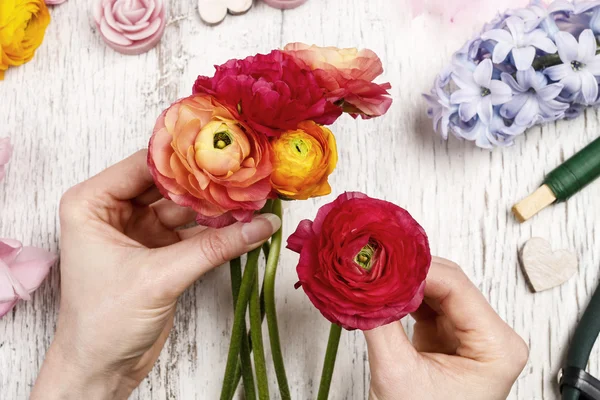 Florist bei der Arbeit. Frau macht Blumenstrauß aus persischem Hahnenfuß — Stockfoto