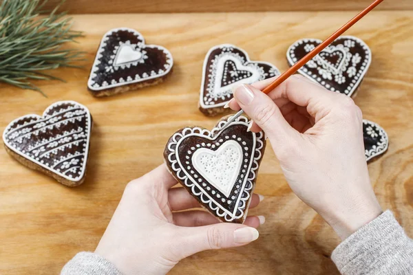 Donna decorazione biscotti di pan di zenzero a forma di cuore — Foto Stock