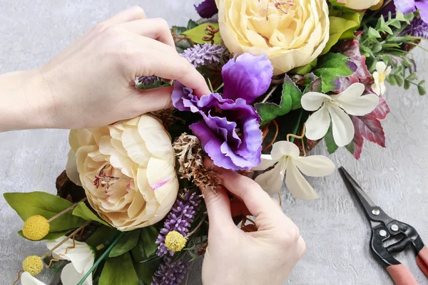Vrouw tabel floral regeling met kunstbloemen maken — Stockfoto