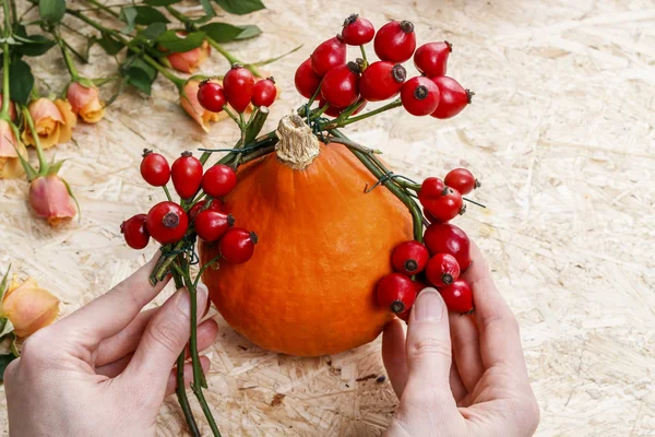 Florista no trabalho: mulher fazendo grinalda com frutas de rosa do quadril (rosa — Fotografia de Stock