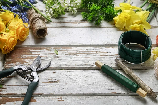 Frühlingsblumen und Gartenaccessoires auf Holzgrund — Stockfoto