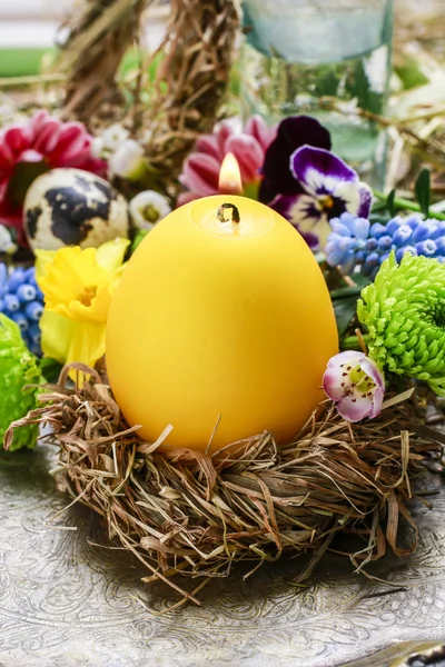 Candle in egg shape on the hay nest. — Stock Photo, Image